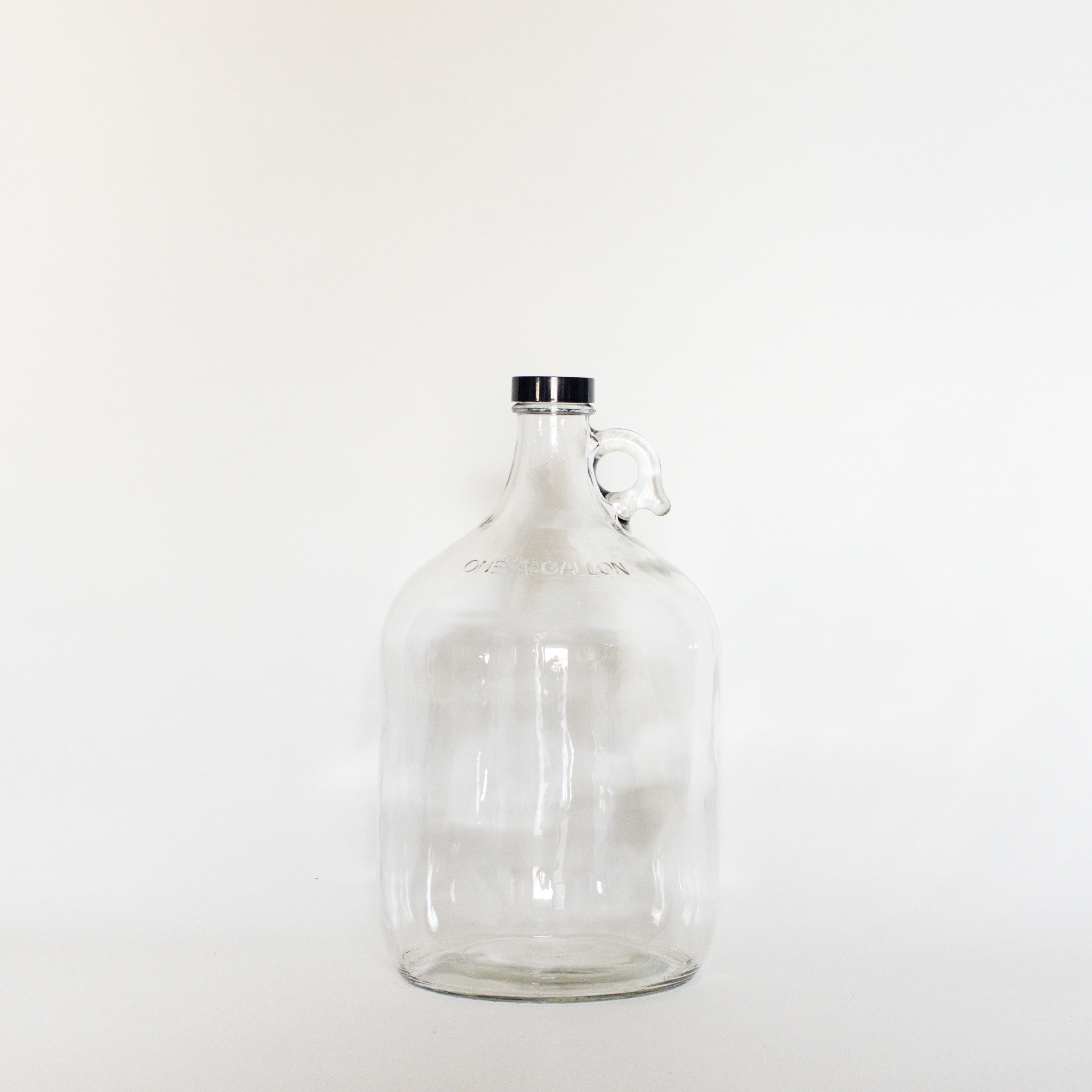 Glass 4 litre growler with white background