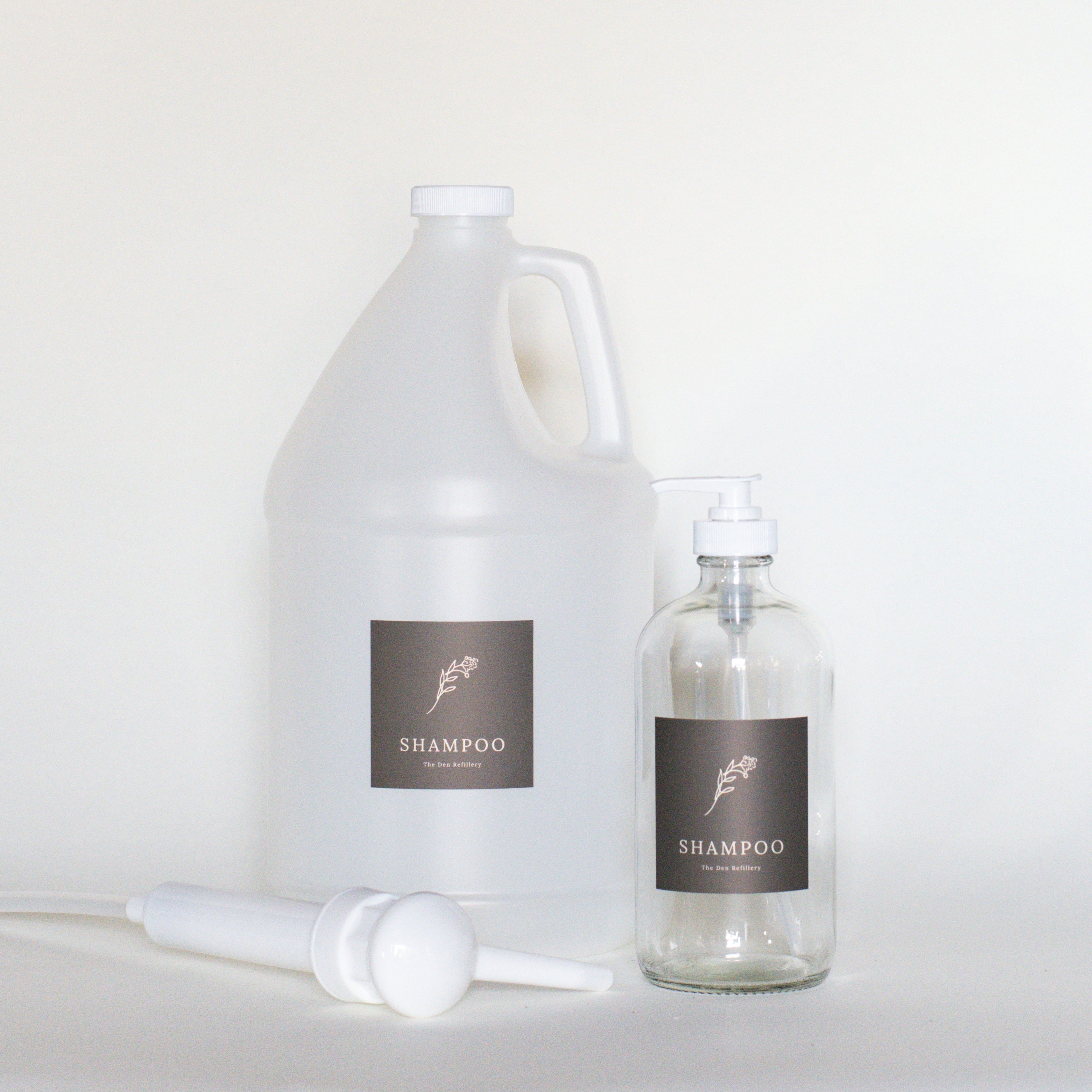 The Den Refillery Shampoo Refill Kit with a 4 Litre jug of Oneka Shampoo and a clear glass bottle